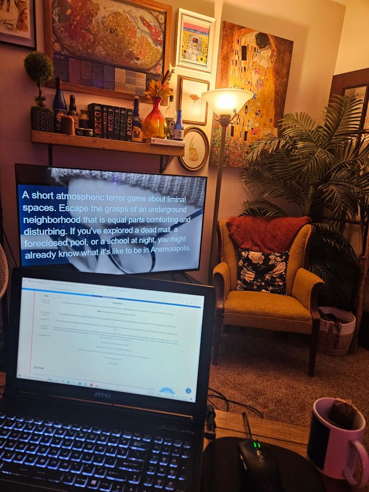 Picture of a living room. In the foreground is a desk with an open laptop and a cup of tea. In the background is a television showcasing a YouTube video of a horror let's play. There is cozy, warm, and colorful decor