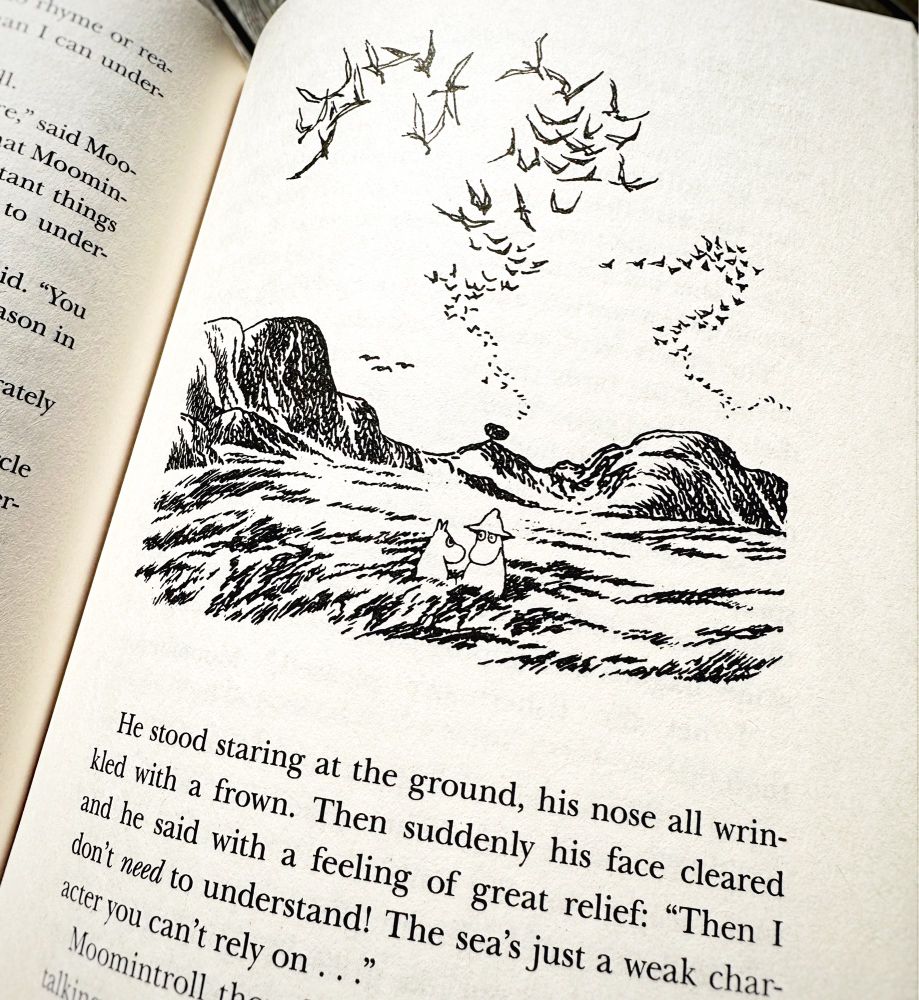 Page from the book Moominpappa at Sea with an illustration showing Moominpappa and Moomintroll on a rocky island with a flock of sea birds overhead