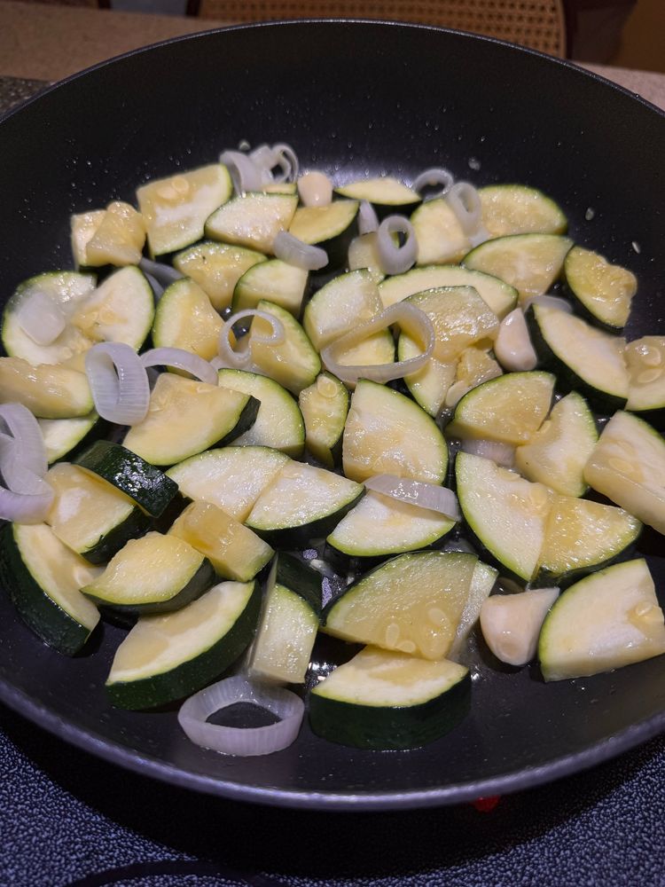 a large pan filled with chopped zucchini, shallots and garlic in olive oil