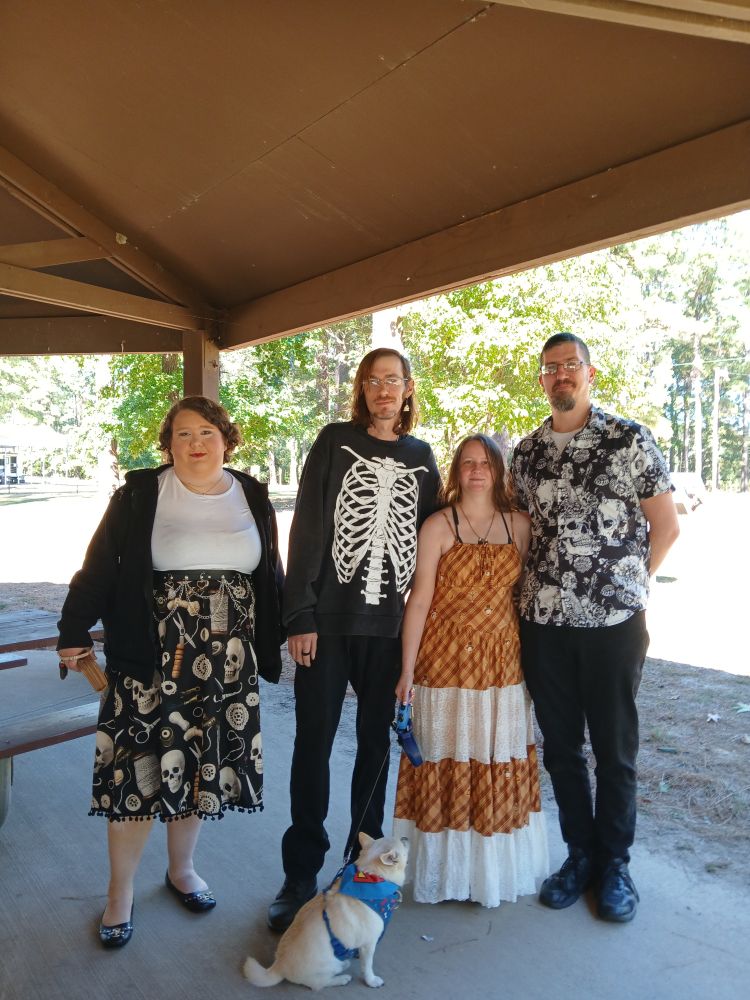 Wedding picture of me in a Howl's Moving Castle inspired dress and Kasey in a skeleton sweater with Gecko in front of us and my friends who made the long journey down here.