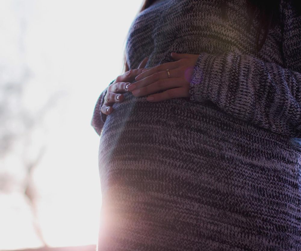 Pregnant person outdoors, holding belly