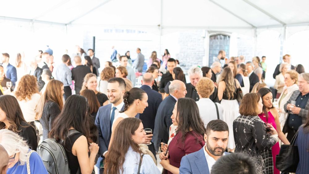 Family, friends, grads under outdoor tent, celebrating