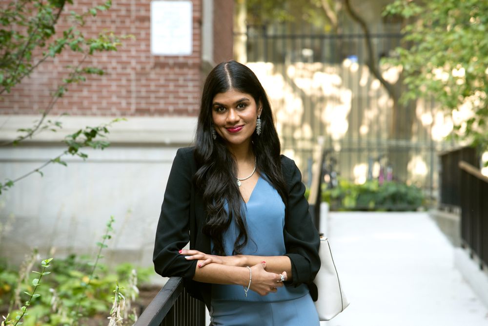 Sivakumar leaning on railing outdoors on campus