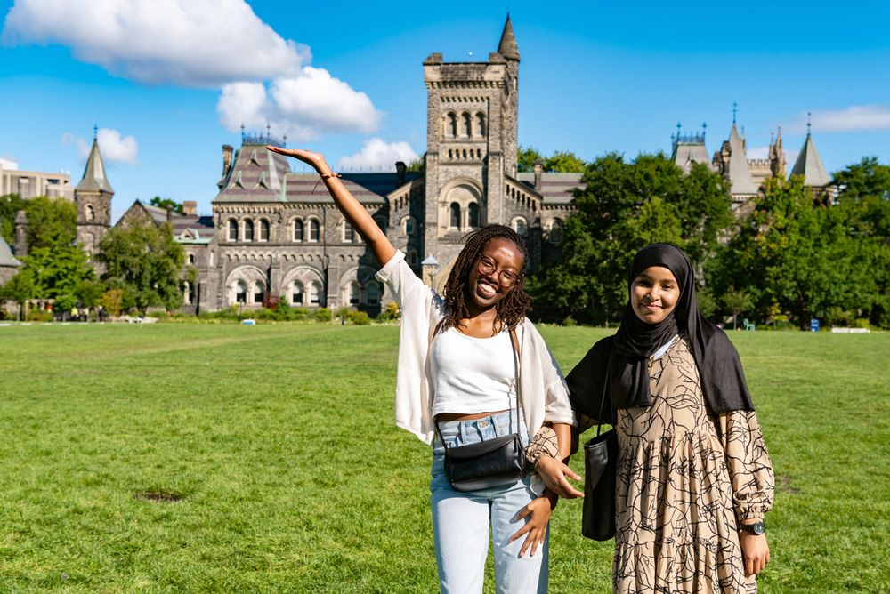 Two women together with university building in the distance