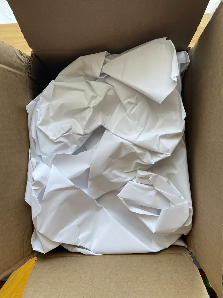 An open shipping box with packing paper on top.
