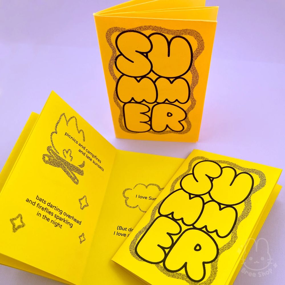 Photo of small mini zines folded out of single sheets of bright yellow and orange papers, in black stacked bubble letters it says “SUMMER” on the covers. An open zine shows inside pages with text and illustrated icons like a campfire.