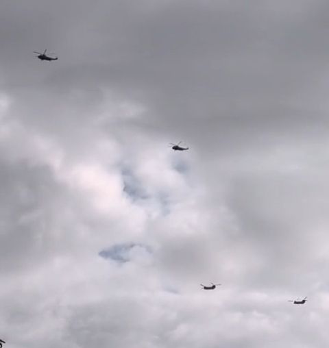 Four helicopters on a grey, cloudy sky. 