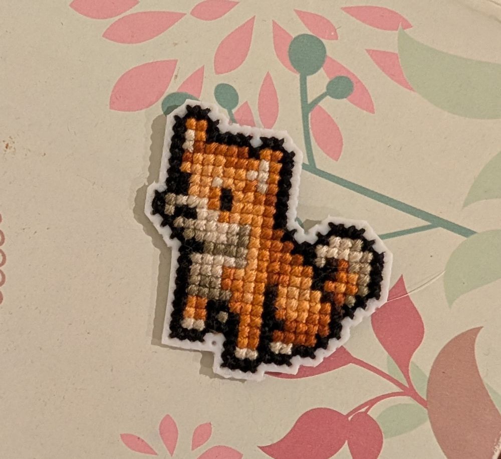 A finished cross stitch of a sesame shiba in