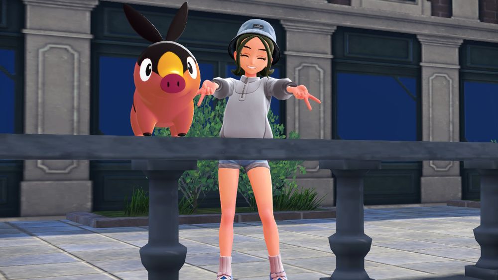 Screenshot from the video game Pokemon Legends: Z-A. It shows my player character, a femme with green shoulder length hair wearing a faded blue bucket hat and matching shorts. They’re also wearing a white, quarter zip pull over and blue sneakers with white, ribbed socks.

They’re posed with their arms out spread, making peace signs with their fingers. On the ledge in front of them sits a Tepig, an orange and black pig-like Pokemon and his name is Tabasco.