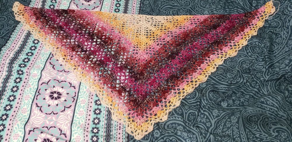 A lacy triangle shawl done in a yellow/pink/burgundy/fuchsia gradient.

Pattern: https://www.hookedbyrobin.com/blog/crochet-fantail-shell-stitch-triangle-shawl