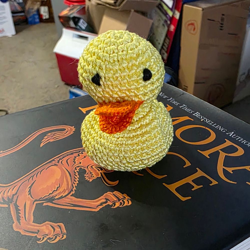 A micro crochet "rubber" duck. Made with 6-strand embroidery floss in yellow with an orange beak and black embroidered eyes. 