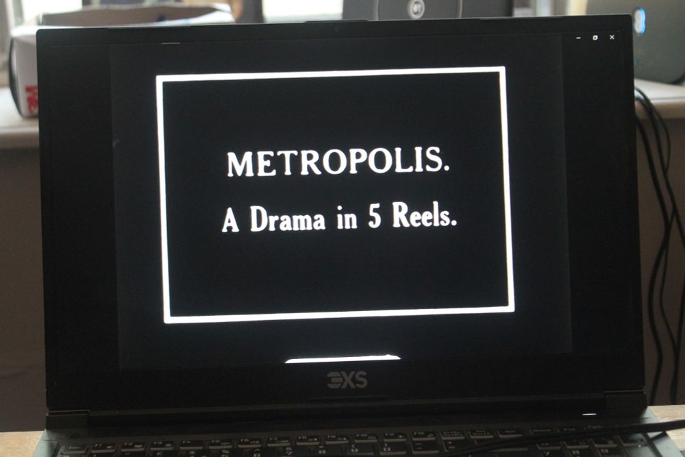 A still from a rare 1 hour version of Metropolis with text -A Drama in 5 Reels- 