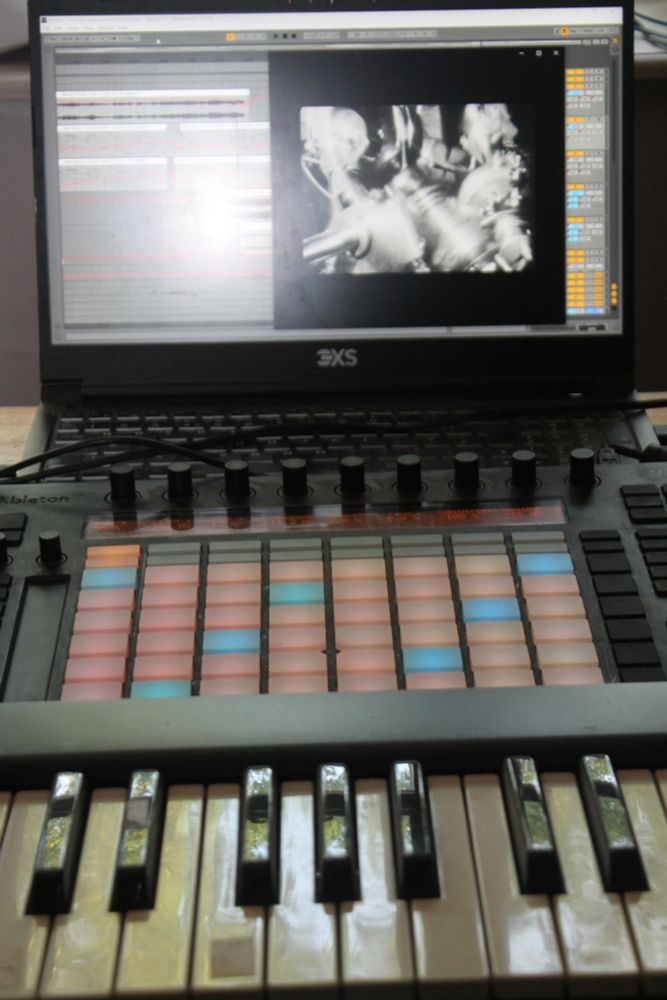 A keyboard, a push controller and a laptop computer screen showing a still from the film Metropolis and Ableton music software
