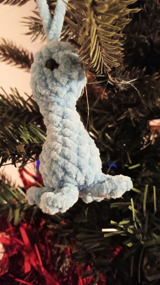 A green crocheted dinosaur on a Christmas tree