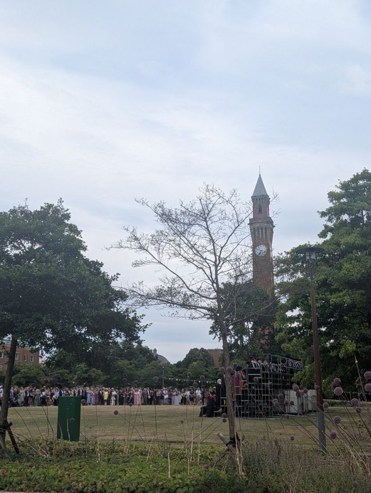 The Green Heart at the University of Birmingham Edgbaston campus with graduates being photographed, watched by their family and friends. Grass and trees and Old Joe look on!