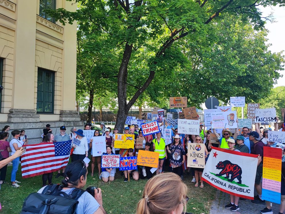 Gruppenbild mit vielen bunten Demoschildern und Amerikanische Flagge
