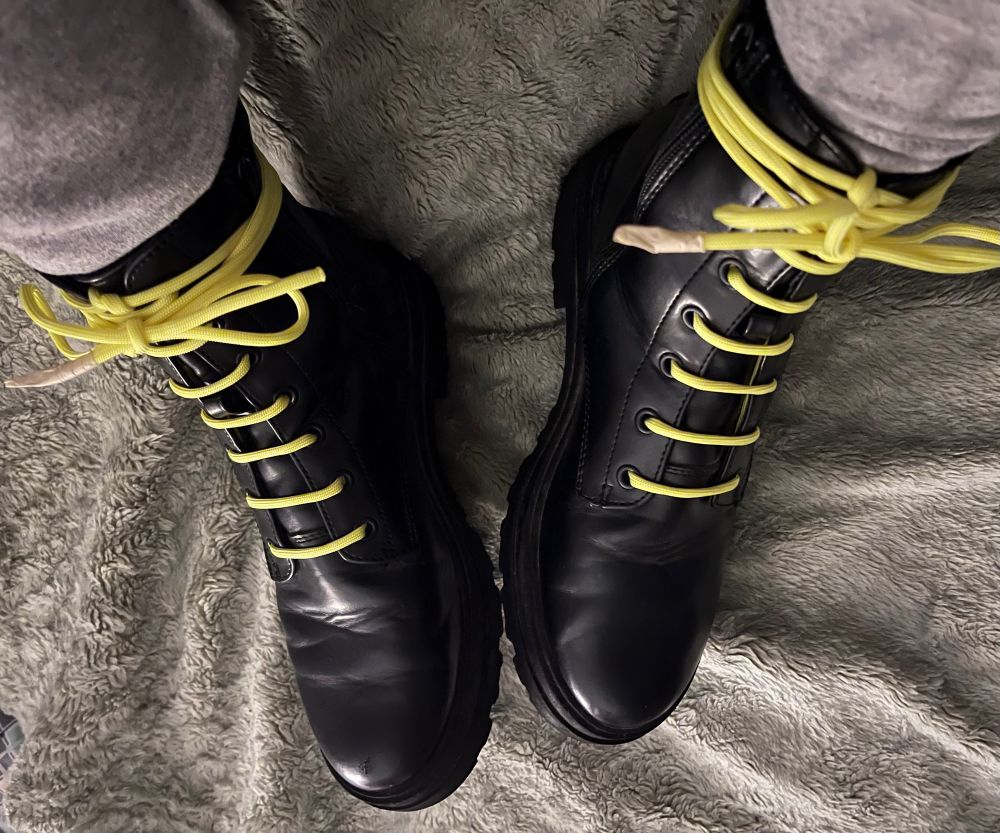 A pair of black boots with bright yellow laces. 