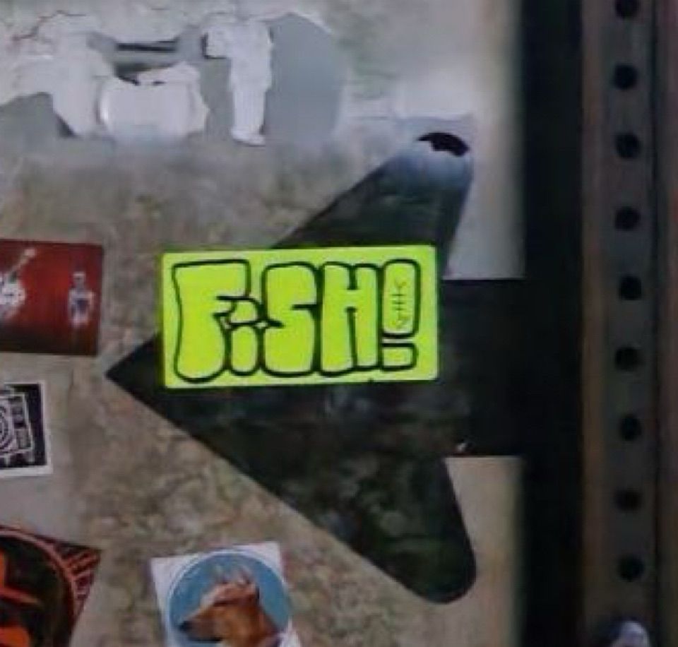 “FISH” label stuck on the back of a sign, a few other stickers are partially visible off to the side.