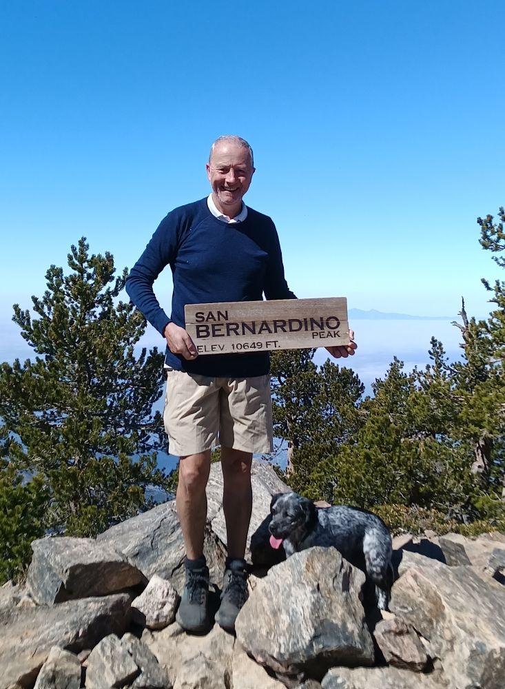 Hike and small spaniel posing on the summit of San Bernardino Peak in southern California
