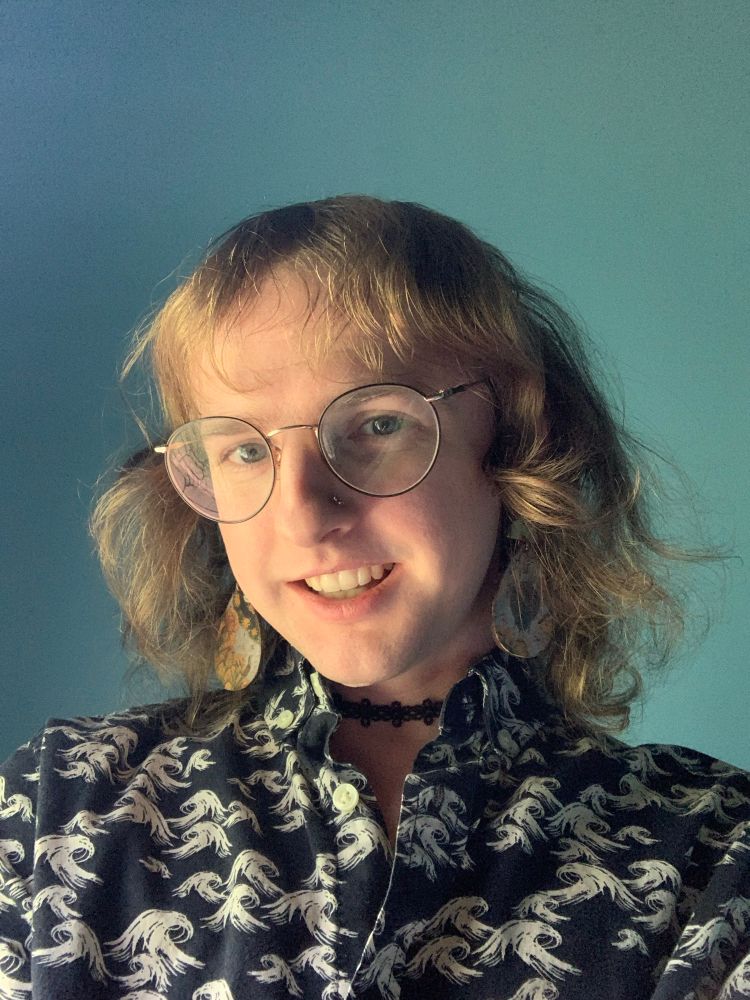 Selfie of me! Blue shirt, blue earrings, blue backgound