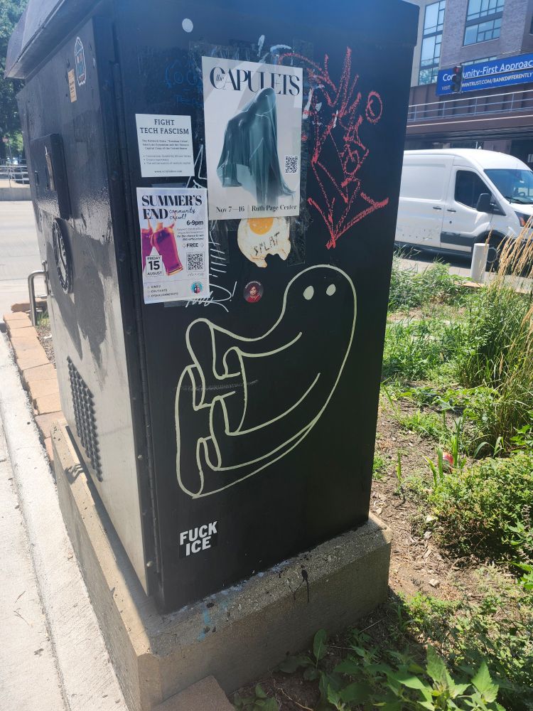 Graffiti of a simple pale yellow lined ghost flying or floating sideways tagged on a traffic signal control cabinet