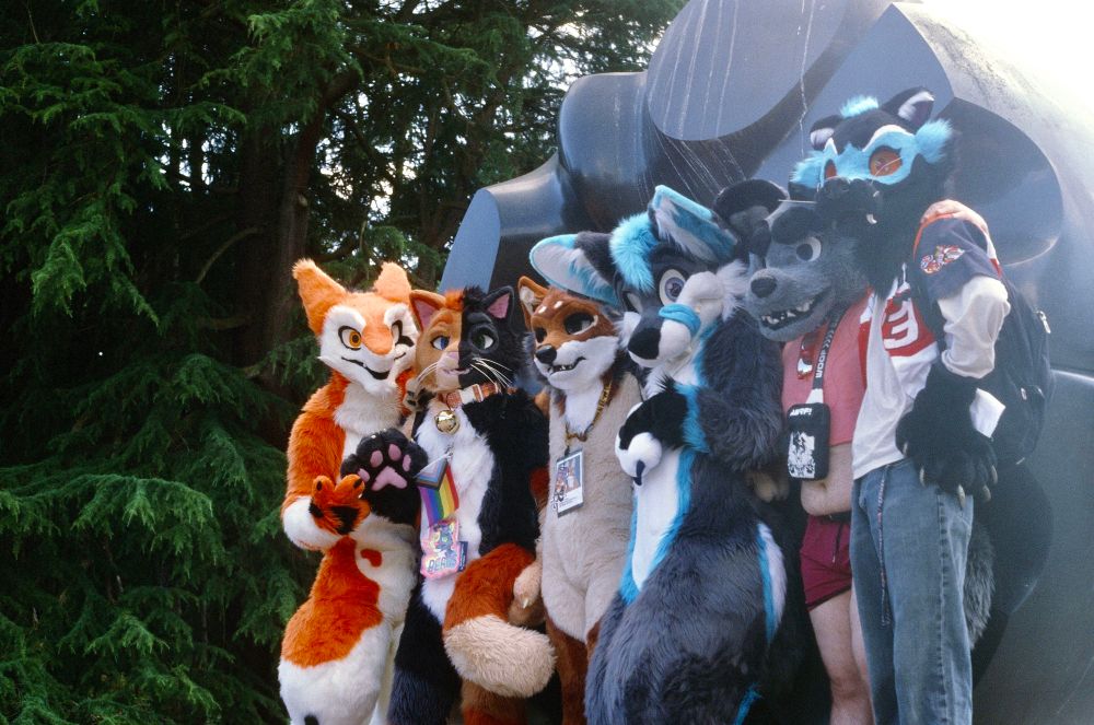 A group of fursuiters pose in front of Black Sun. From left to right, we have Rikal, Beans, Cooper, Dex, Cartoon, and Pronto