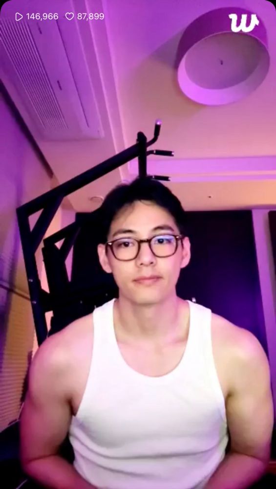 A screenshot of Tae’s Weverse live in which he is wearing a white tank top and black framed glasses. His arms and shoulders look INCREDIBLE