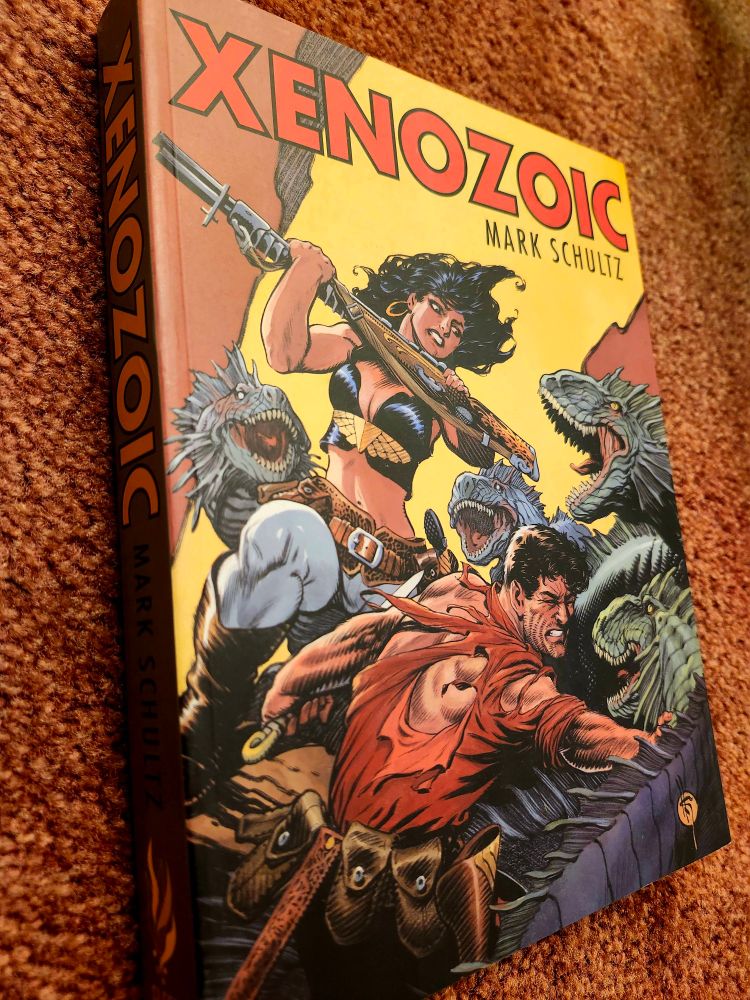 The cover of a Xenozoic Tales omnibus. It shows the leads, Jack and Hannah, fighting off a horde of carnivorous dinosaurs.