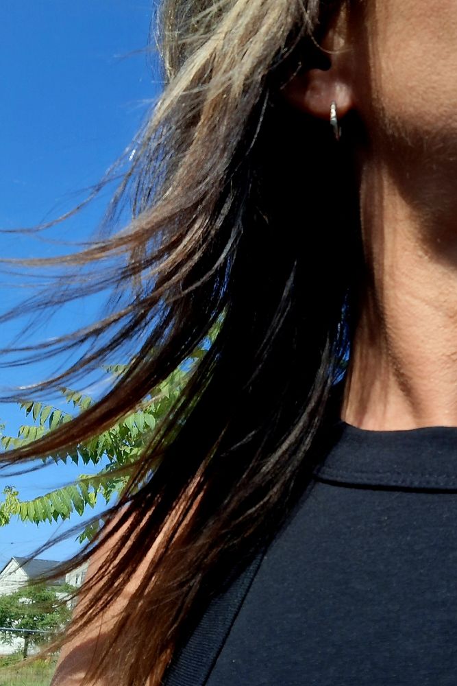 Halbes Selfie von der Seite. Mit blauem Himmel im Hintergrund. 