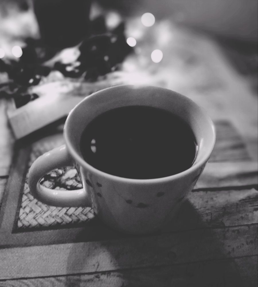 Meine Tasse Kaffee auf dem Tisch. Im Hintergrund ein kleiner Adventskranz mit Beleuchtung. 