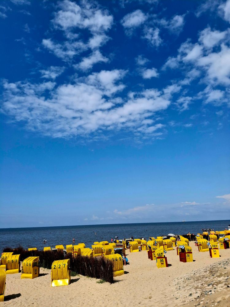 Blauer Himmel. Ein paar Wolken. Strandkörbe und im Hintergrund die Nordsee. 


