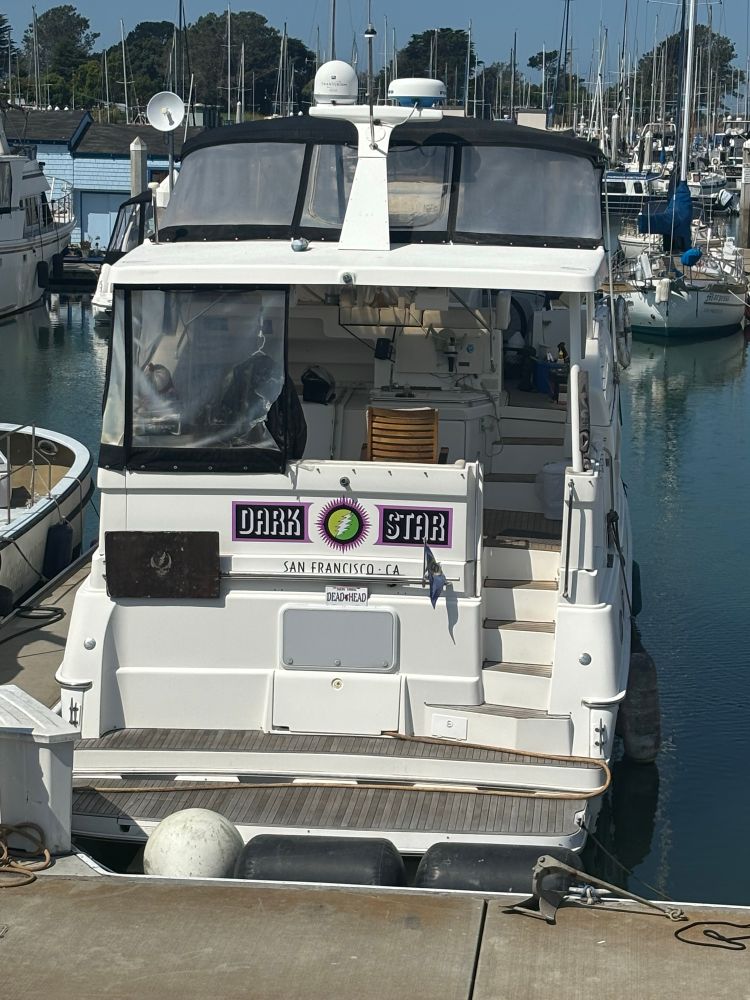 A photo taken at the Berkeley Marina of a small yacht named the Dark Star with a Grateful Dead skull in the middle of the name. It is registered in San Francisco, California.