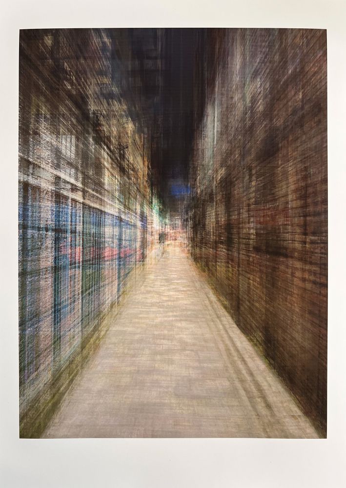 An abstract, blurred image of an urban alleyway at night, viewed from a slightly elevated perspective looking down a long, narrow path. The sides of the path are lined with dark, vertical forms that suggest buildings, with horizontal streaks of light and color that imply windows or signs. The path itself is lighter, with faint horizontal lines indicating paving. The overall effect is one of motion and speed, with colors muted but visible, creating a sense of a bustling city scene in motion.
