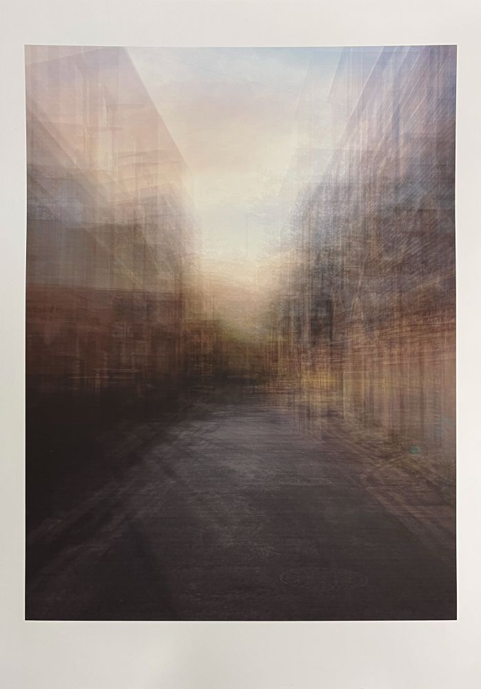 A digitally layered, semi-abstract image of an empty urban street flanked by buildings on both sides, fading into a softly glowing light at the horizon. The multiple exposures create a dreamlike, painterly effect with blurred architectural details and a warm, atmospheric sky above.