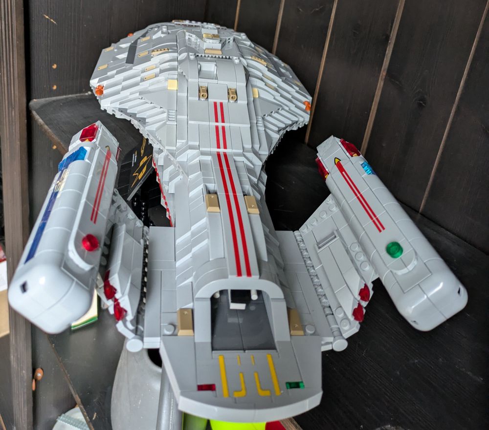 a model of the USS Voyager from the Star Trek franchise made from Lego like bricks, rear view, a small shuttle visible in the shuttle ramp