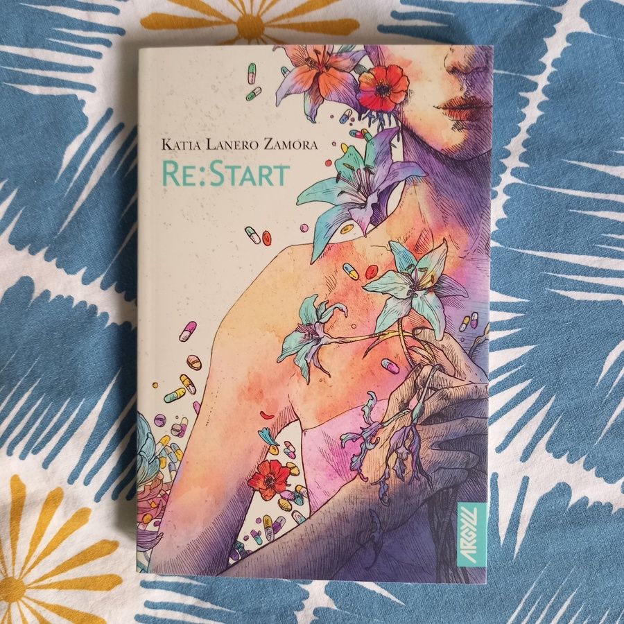 Re:Start, une novella de Katia Lanero Zamora parue dans la collection RéciFs chez Argyll. La couverture montre une femme, les épaules nues, des fleurs dans les mains et au niveau de son visage avec des gélules et des comprimés de toutes les couleurs autour d'elle