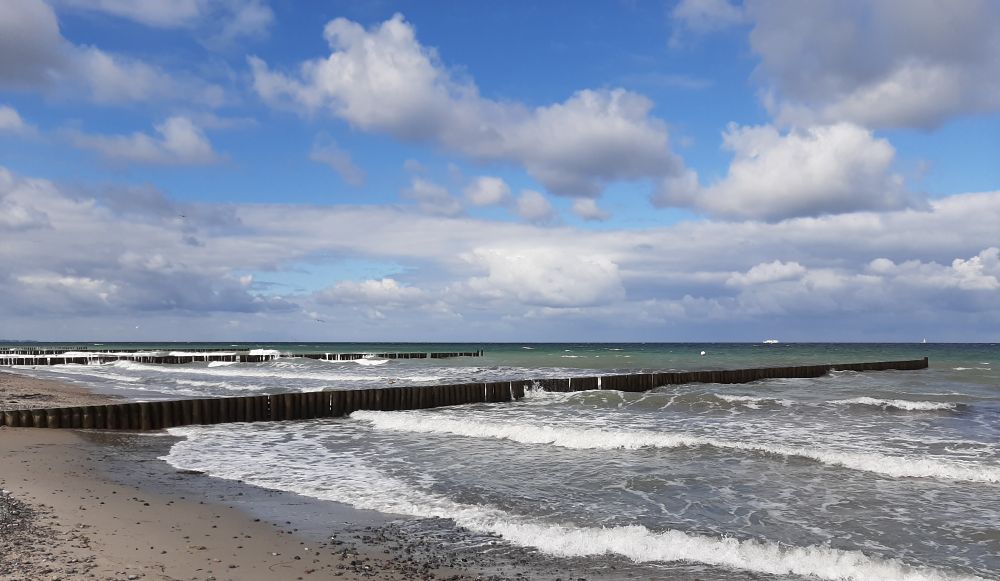Ostseepanorama, blauer Himmel mit Wolkenfeldern, Brandung, Buhnen.