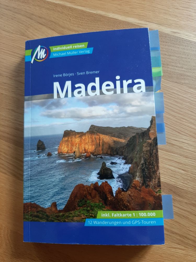 Reiseführer von Madeira mir vielen Lesezeichen liegt auf einem Holztisch.