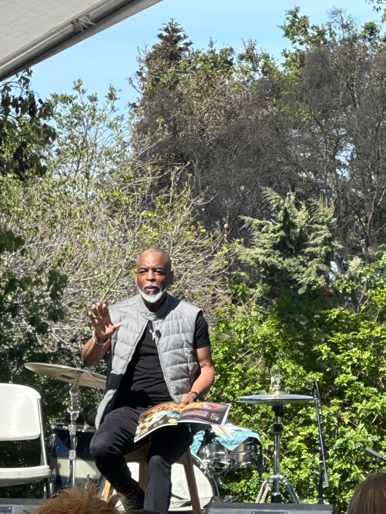Levar Burton reading a book with trees in the background 