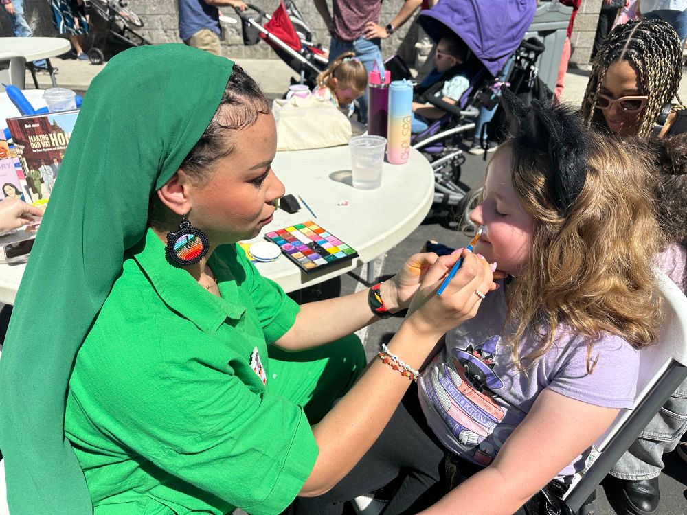 Blair Imani paints the face of a girl wearing cat ears 