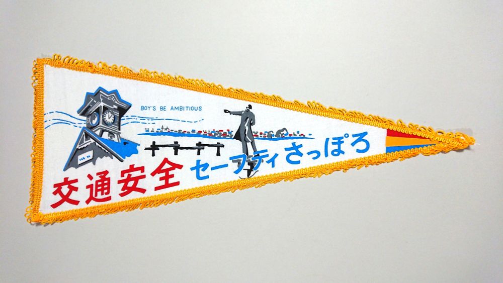 1, 交通安全（札幌）のペナント。白い布にイラストをプリント。黄色いモール装飾付き。