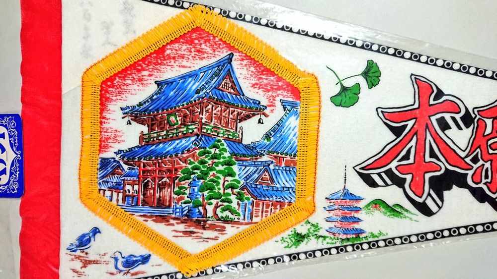 2, イラストの拡大。御影堂門が描かれている。高さ27メートルで、世界最大級とされる木造二重門。イラストは簡略化されていて可愛らしい印象。周囲に鳩、いちょうの葉、五重塔と大文字山が描かれている。