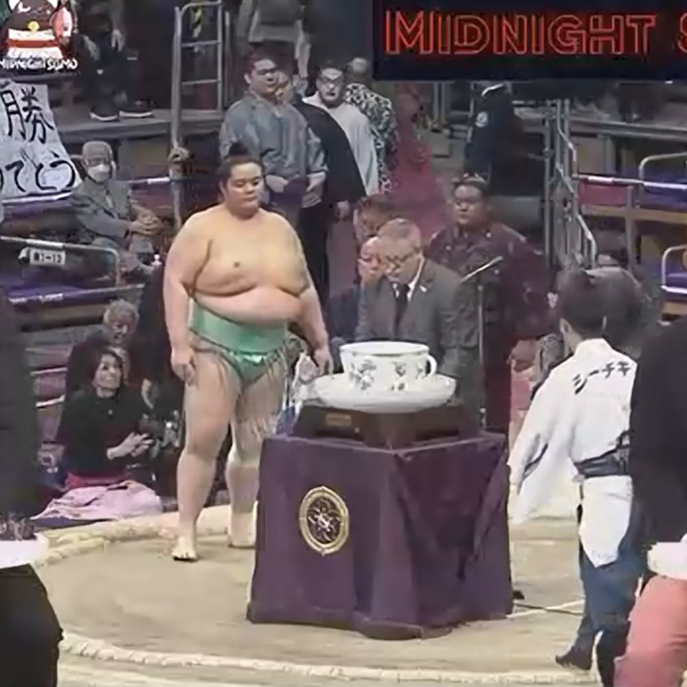 A screenshot of a giant teacup being awarded to a sumo wrestler after a tournament.