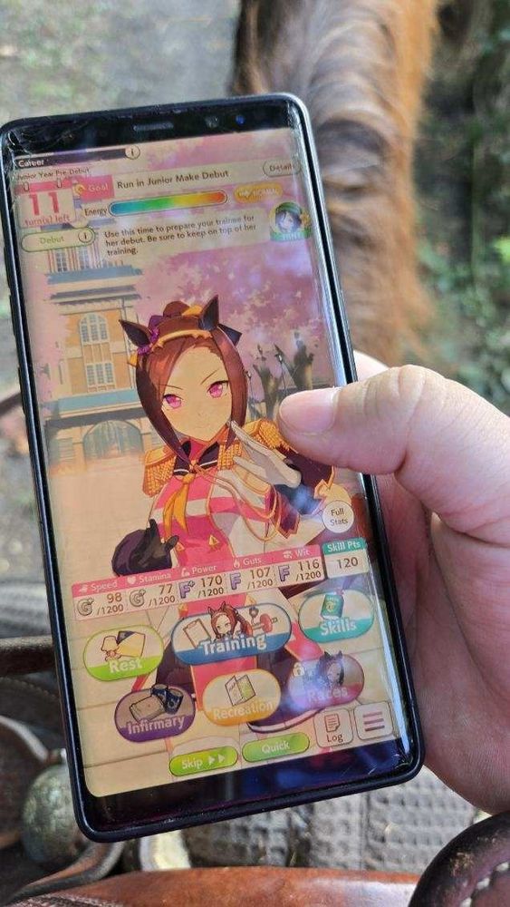 a phone with uma musume open held while on a horse