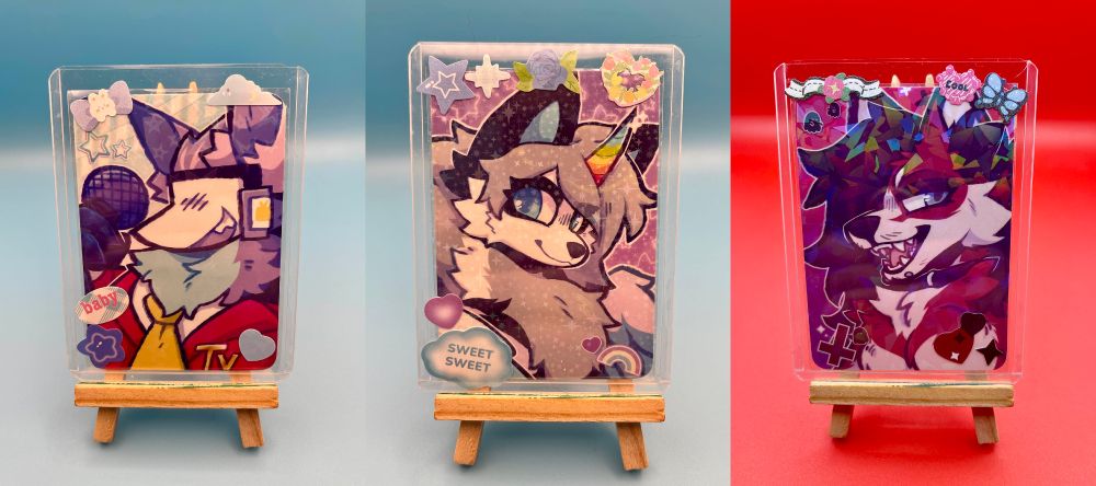 Three photocards sitting on a small easel with holographic stickers and film on them. Photocards are popular in the KPOP scene, often decorated with stickers like these!