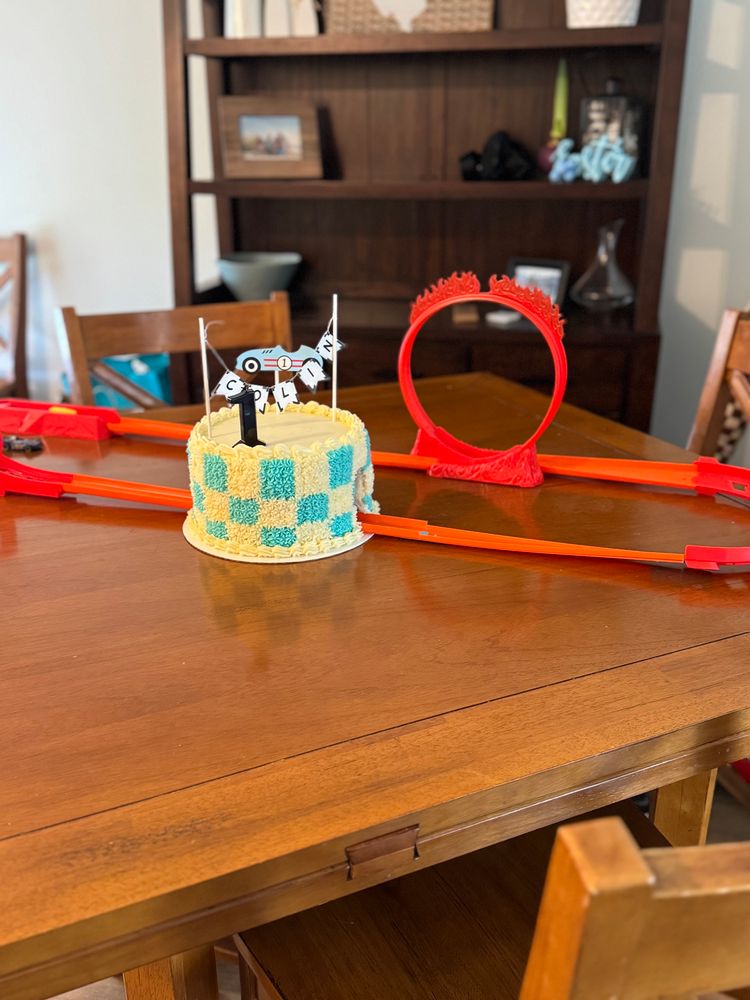 Checkered birthday cake with a hot wheels track going through a tunnel. 
