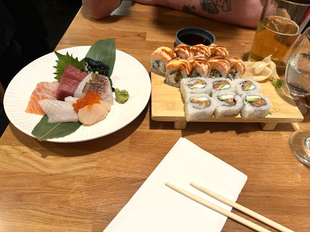 Several rolls of sushi and pieces of sashimi on a table. 
