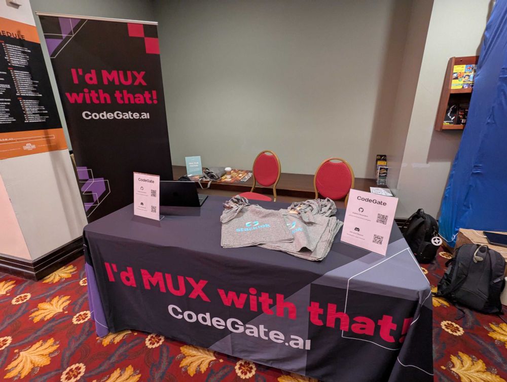 The codegate.ai booth at the All Things Open AI conference in Durham, NC. The banner says "I'd MUX with that!"