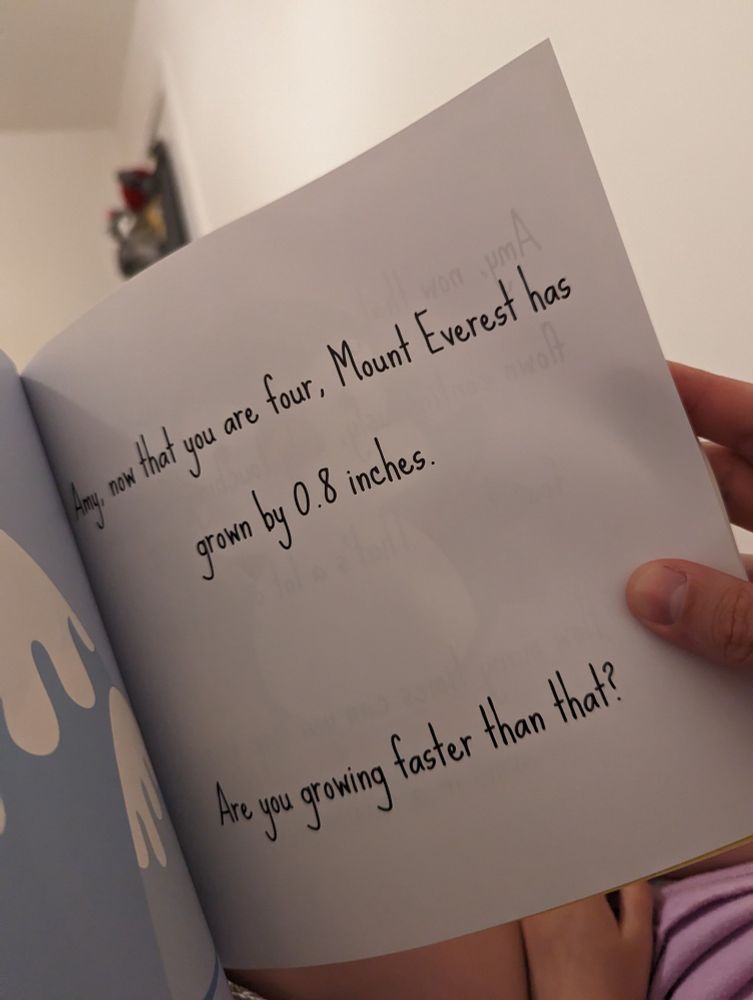 A page of a children's book which reads "Amy now that you are four, Mount Everest has grown by 0.8 inches. Are you growing faster than that?"