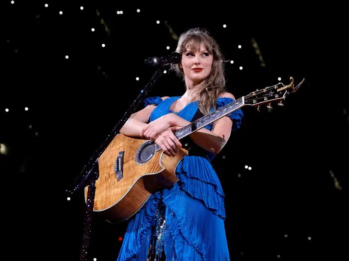 taylor during la night 6 surprise song set for 1989tv teaser
she's wearing the blue dress x holding a guitar x smirking while looking off to her left side